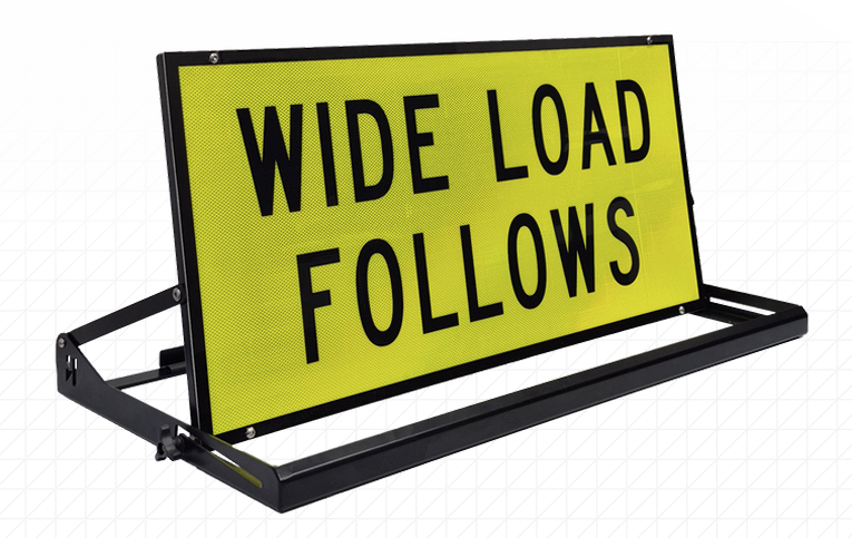 Pillot Vehicle Sign Rig » Highway 1 Bright yellow warning sign reading 'WIDE LOAD FOLLOWS' mounted on a black metal frame and stand.