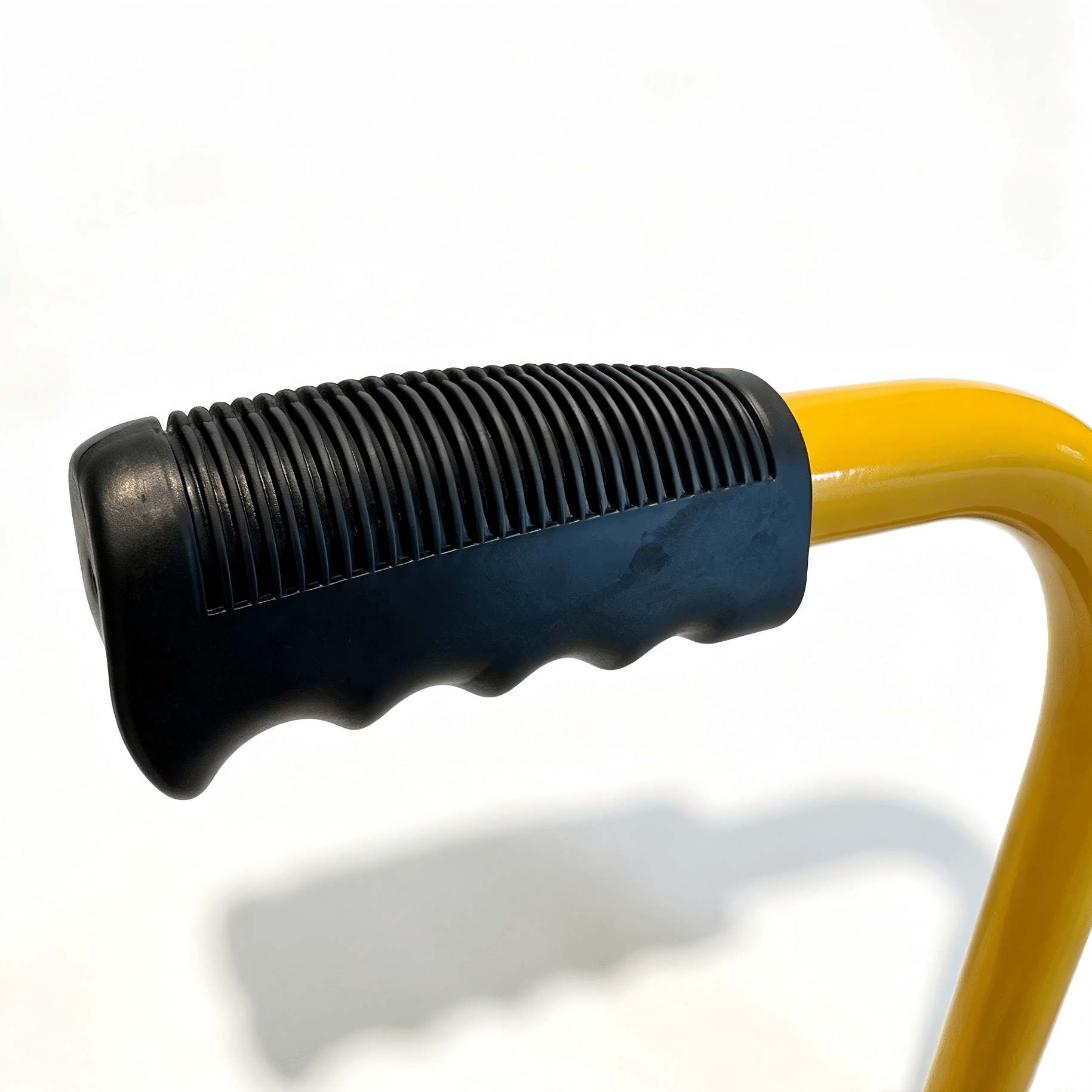 Wheel Chock Handle » Highway 1 Close-up of a black ribbed handle with a yellow curved tool body visible at the end.