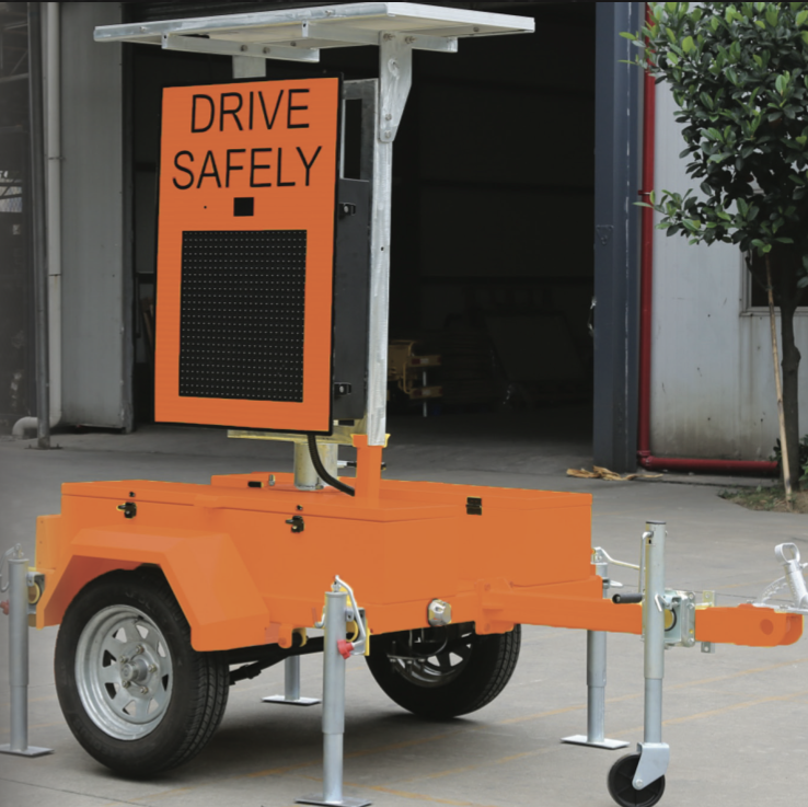 Screenshot 2026-09-22 at 74717 AM » Highway 1 Orange portable safety display on trailer reading 'DRIVE SAFELY' with a perforated black panel, mounted above a wheeled orange base with outriggers.