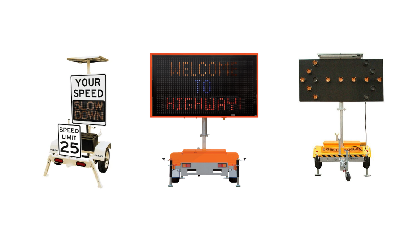 Portable road signs on trailers: left shows 'Your Speed Slow Down' with speed limit 25; middle is an electronic message board reading 'WELCOME TO MICHIGAN'; right is a large LED sign on a trailer with a black panel.